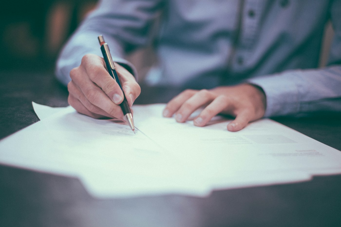 A hand signing a document with a fountain pen