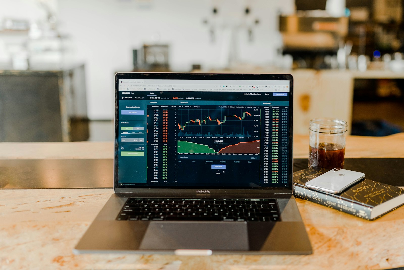 A laptop showing a market chart on a wooden desk