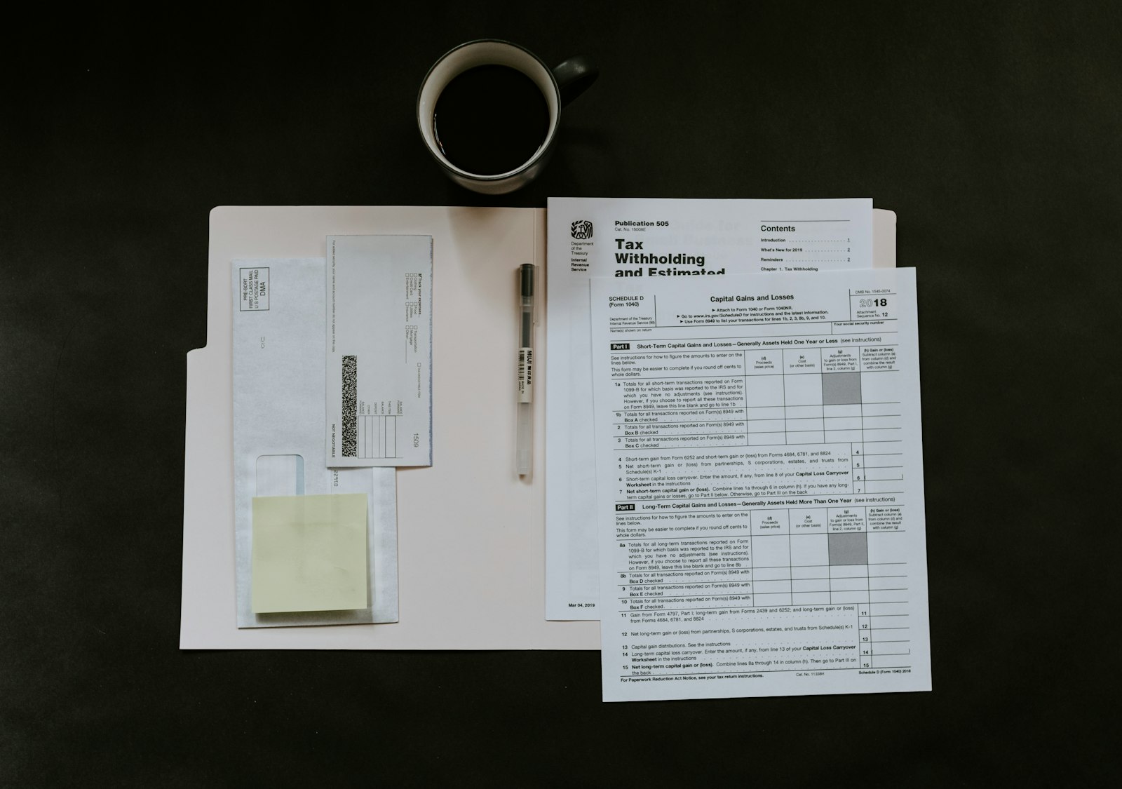 Tax forms and a pen laid out on a dark desk